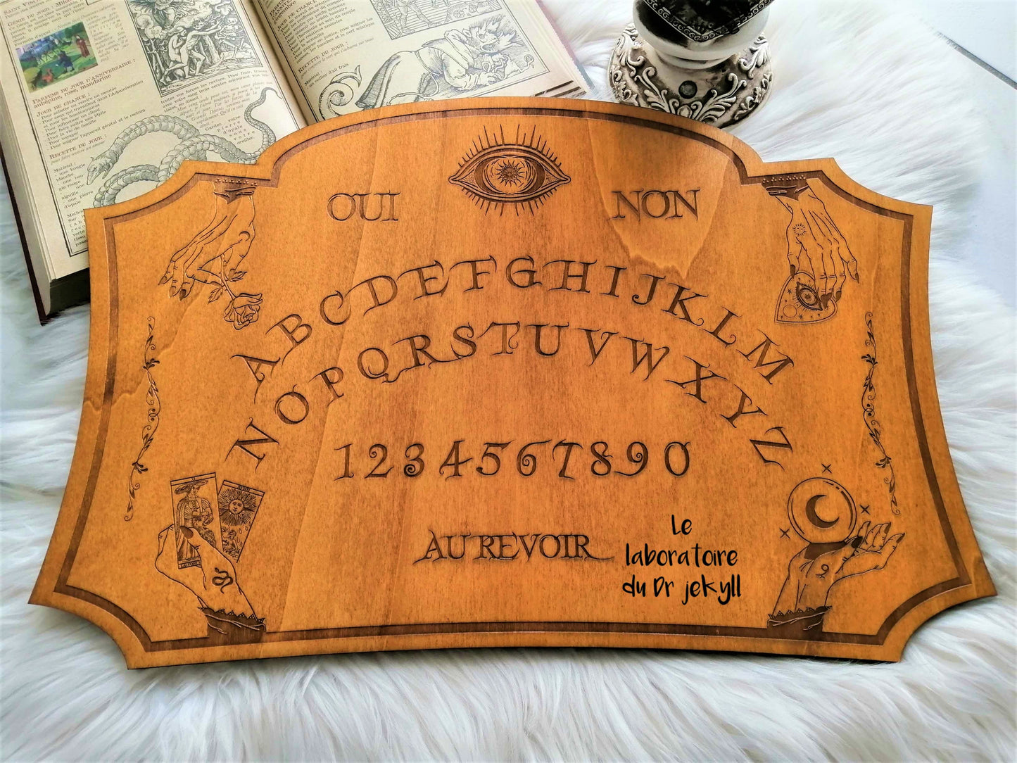 Planche Ouija 'Mystique' artisanale, fabriquée à la main avec un bois de qualité supérieure (50 cm x 33 cm). Chaque pièce est unique, offrant une fusion parfaite entre l'art ésotérique et l'artisanat français. Idéale pour les séances de divination, le spiritisme ou comme décoration mystique dans votre intérieur. Personnalisation possible avant l'achat. Un objet unique pour les passionnés d'arts occultes et de spiritualité